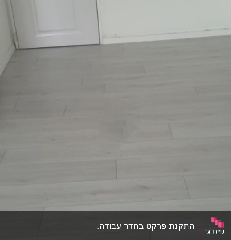 רצפת פרקט עץ בהירה בחדר ריק עם דלת לבנה